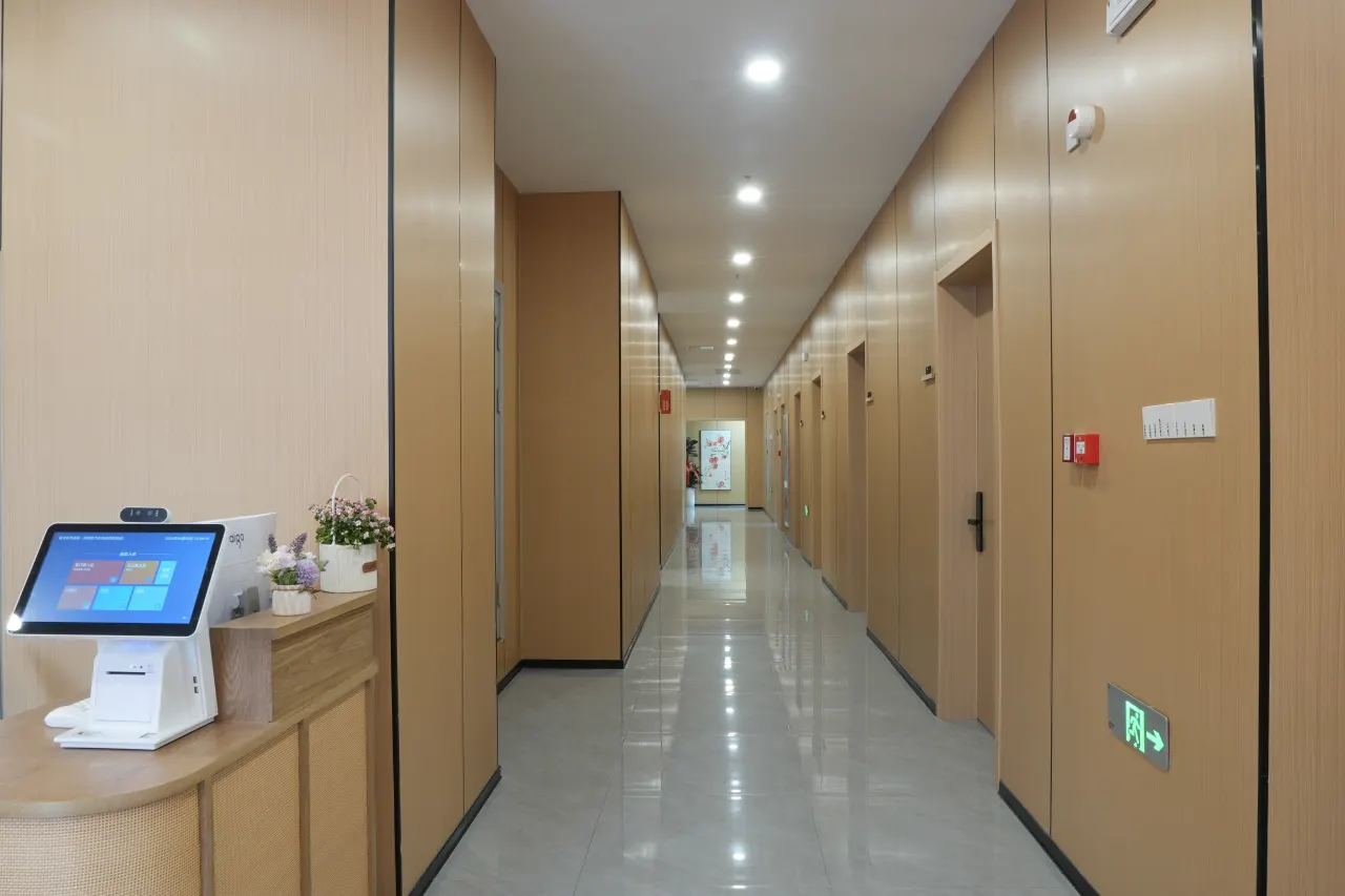 橘舍青年酒店合肥高新区汽车西站地铁站店客房走廊实拍：疏散指示灯与手动报警按钮全程可见，通道上没有任何堆放
